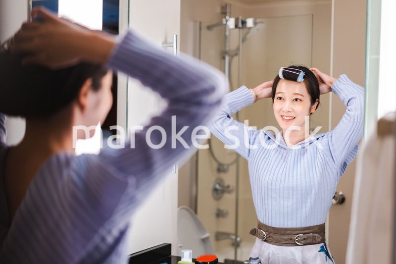 鏡の前で髪のセットをする若い女性