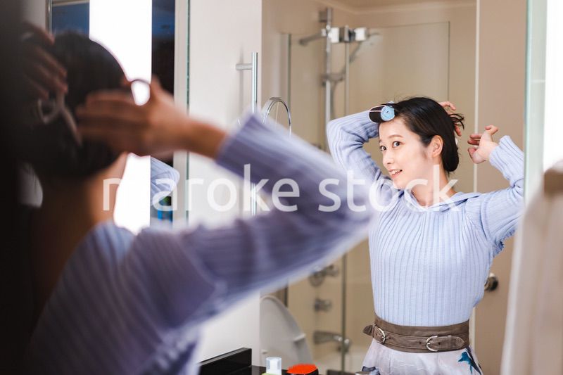 鏡の前で髪のセットをする若い女性