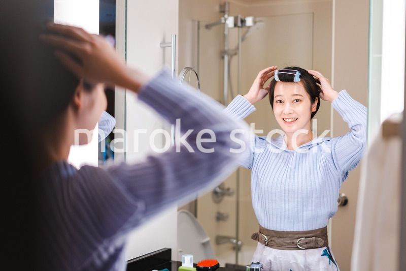 鏡の前で髪のセットをする若い女性