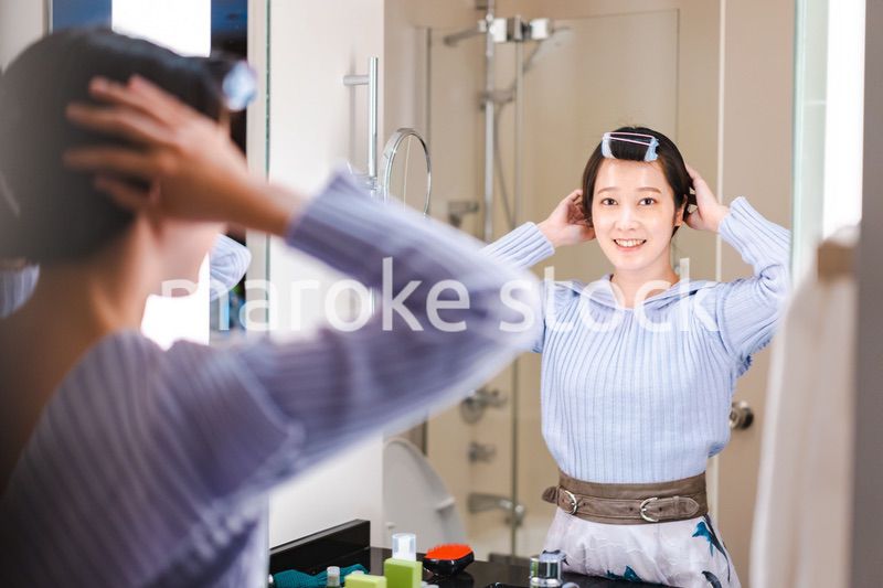 鏡の前で髪のセットをする若い女性