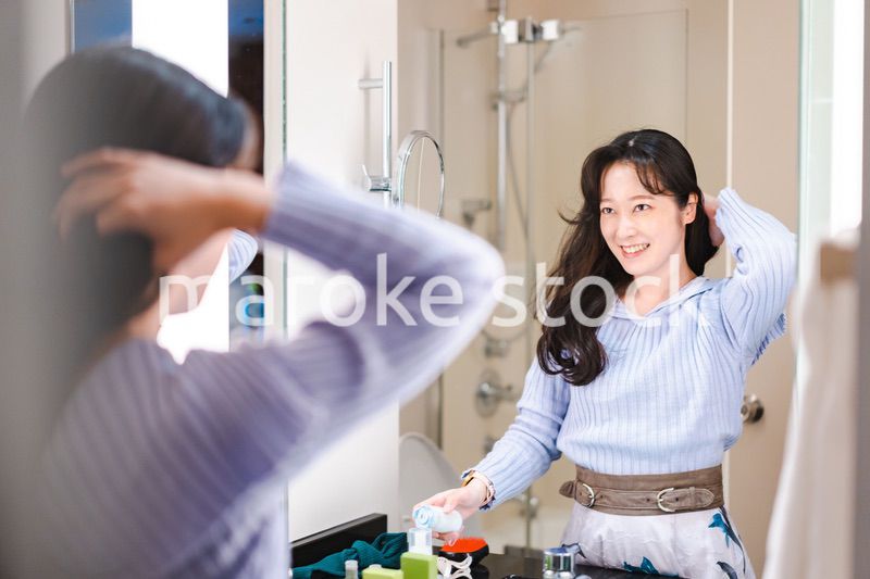 鏡の前で髪のセットをする若い女性