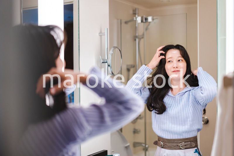 鏡の前で髪のセットをする若い女性