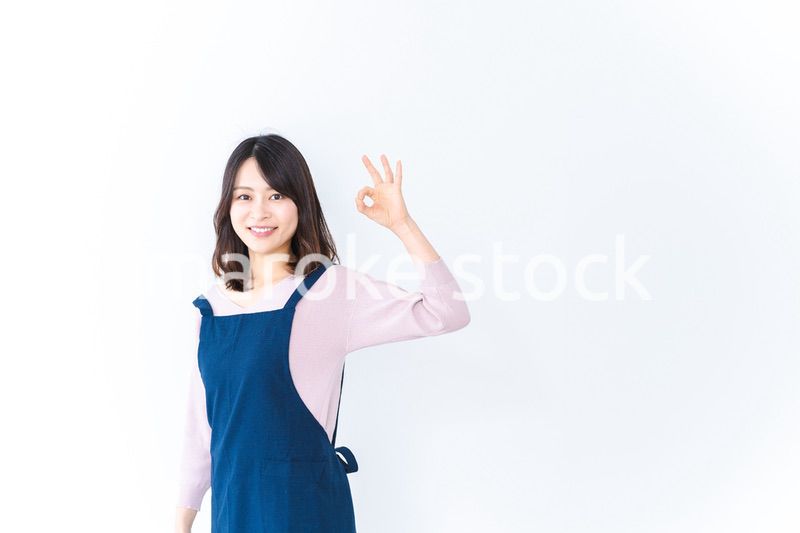 エプロンを着てOKサインを示す若い女性