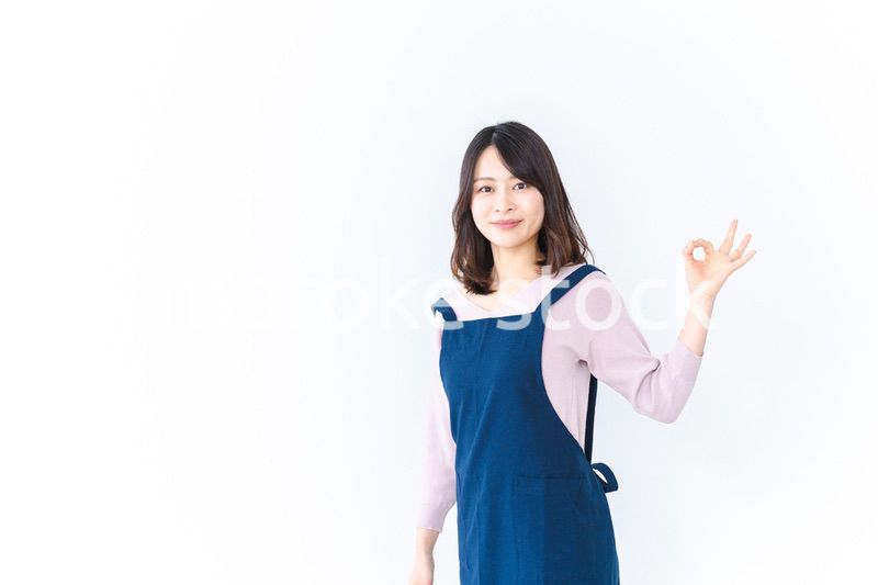エプロンを着てOKサインを示す若い女性