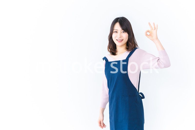 エプロンを着てOKサインを示す若い女性