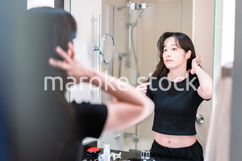 鏡の前で髪のセットをする若い女性