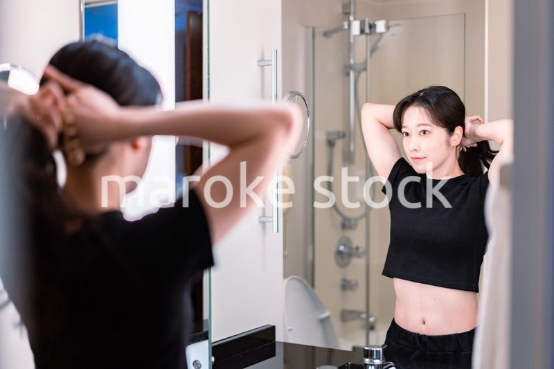 鏡の前で髪のセットをする若い女性