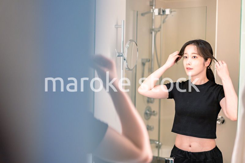 鏡の前で髪のセットをする若い女性
