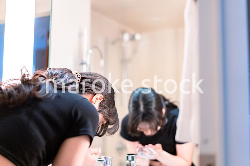洗面所で洗顔をする若い女性