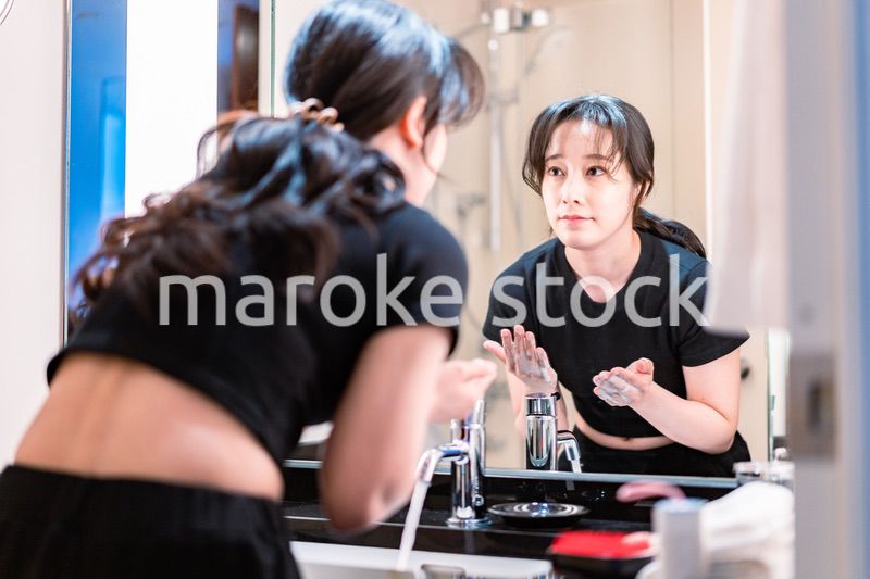 洗面所で洗顔をする若い女性