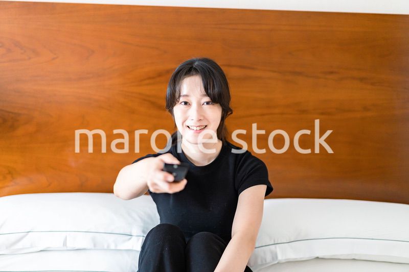 テレビをリモコンで操作する若い女性