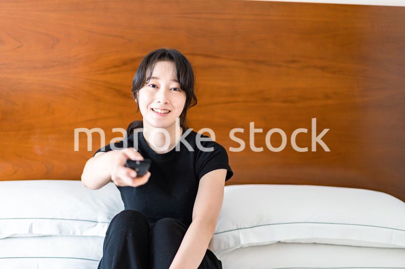 テレビをリモコンで操作する若い女性