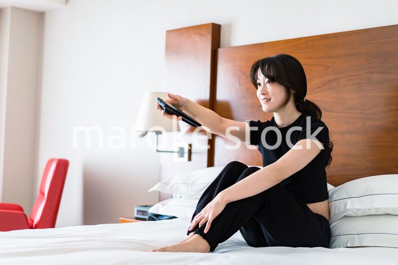テレビをリモコンで操作する若い女性