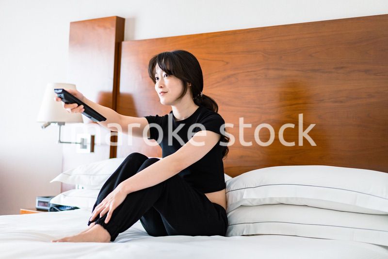 テレビをリモコンで操作する若い女性