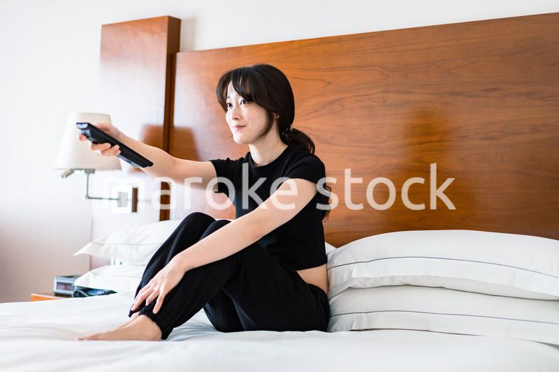 テレビをリモコンで操作する若い女性