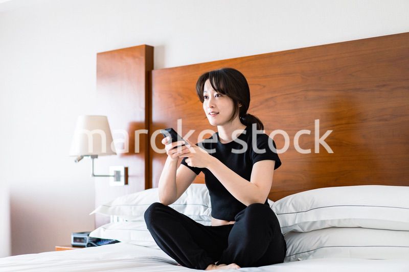 テレビをリモコンで操作する若い女性