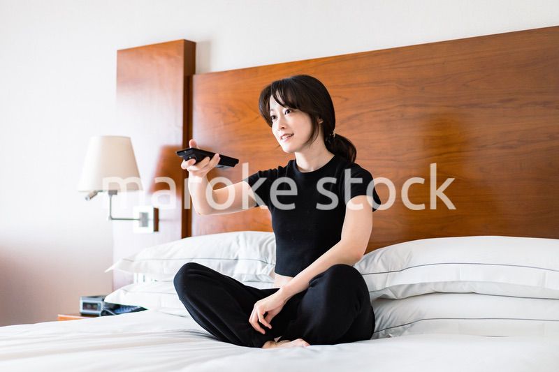 テレビをリモコンで操作する若い女性