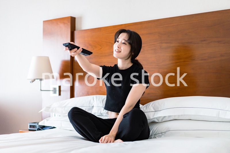 テレビをリモコンで操作する若い女性
