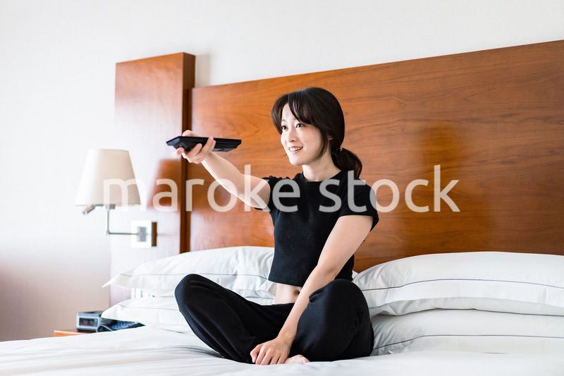 テレビをリモコンで操作する若い女性