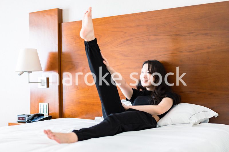 ベッドでストレッチをする若い女性