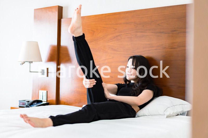 ベッドでストレッチをする若い女性