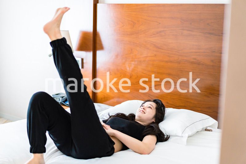 ベッドでストレッチをする若い女性