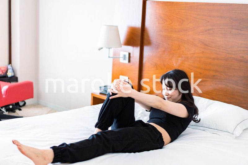 ベッドでストレッチをする若い女性