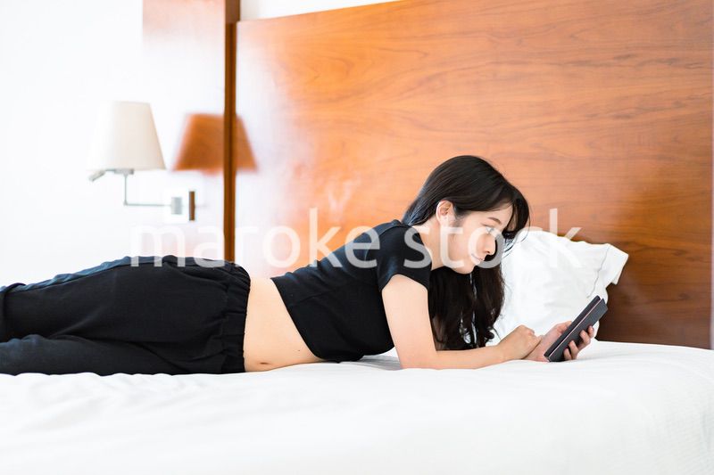 ベッドで電子書籍を読む若い女性