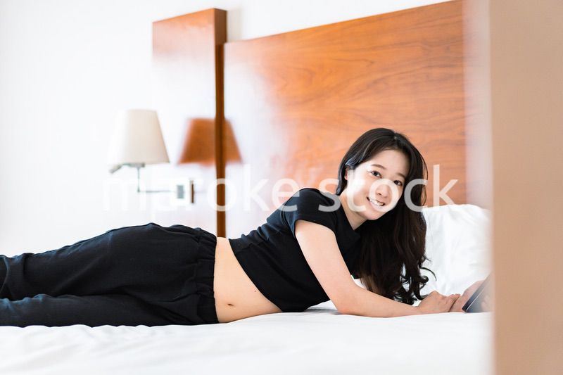 ベッドで電子書籍を読む若い女性