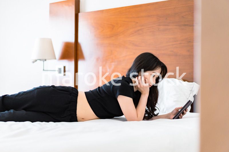 ベッドで電子書籍を読む若い女性