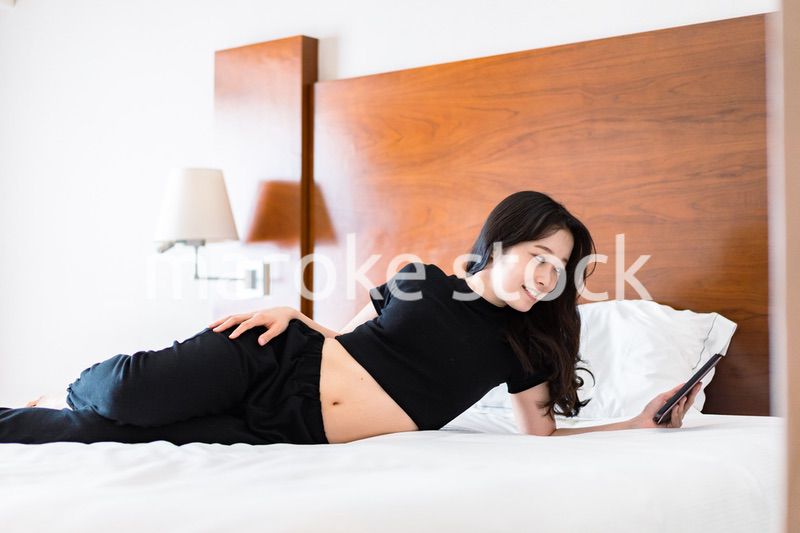 ベッドで電子書籍を読む若い女性