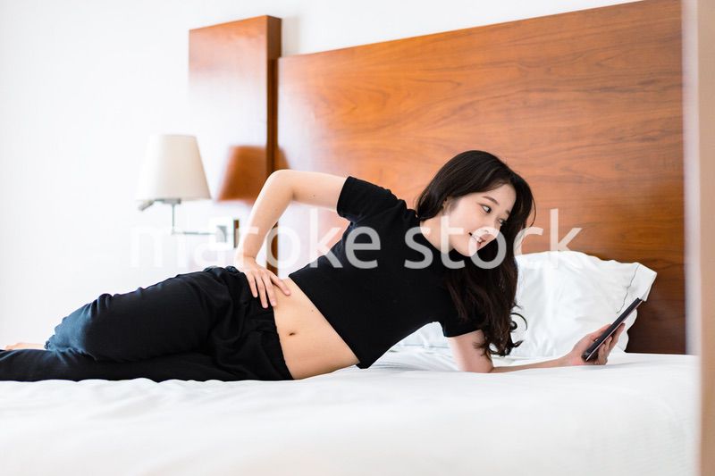 ベッドで電子書籍を読む若い女性