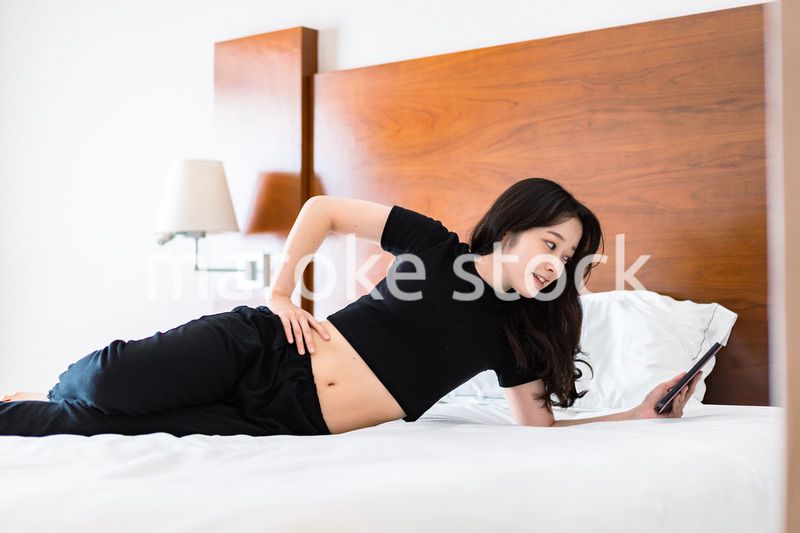 ベッドで電子書籍を読む若い女性