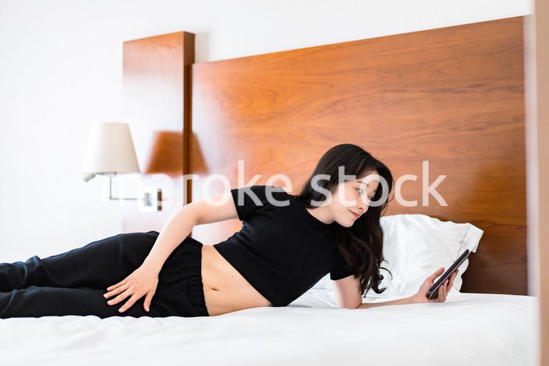 ベッドで電子書籍を読む若い女性