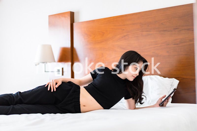 ベッドで電子書籍を読む若い女性