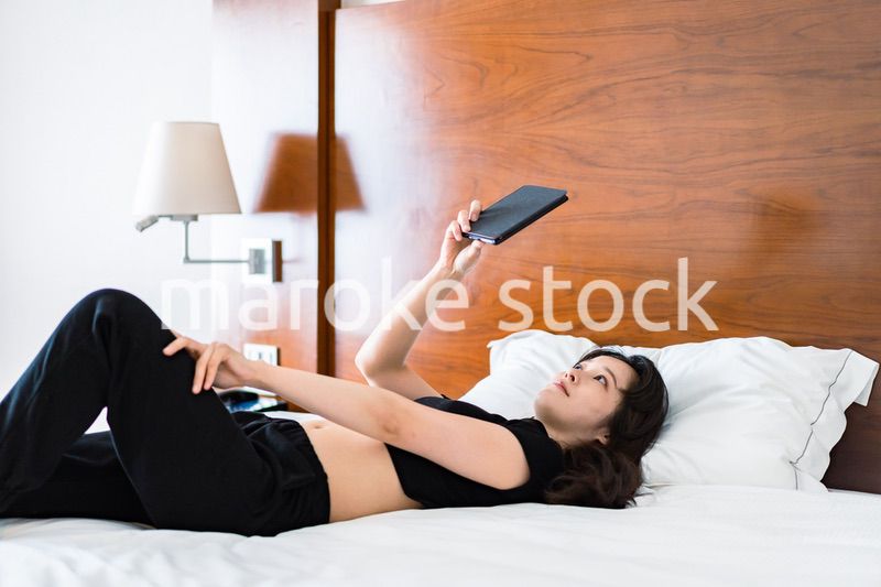 ベッドで電子書籍を読む若い女性