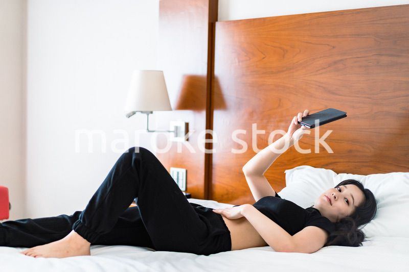 ベッドで電子書籍を読む若い女性