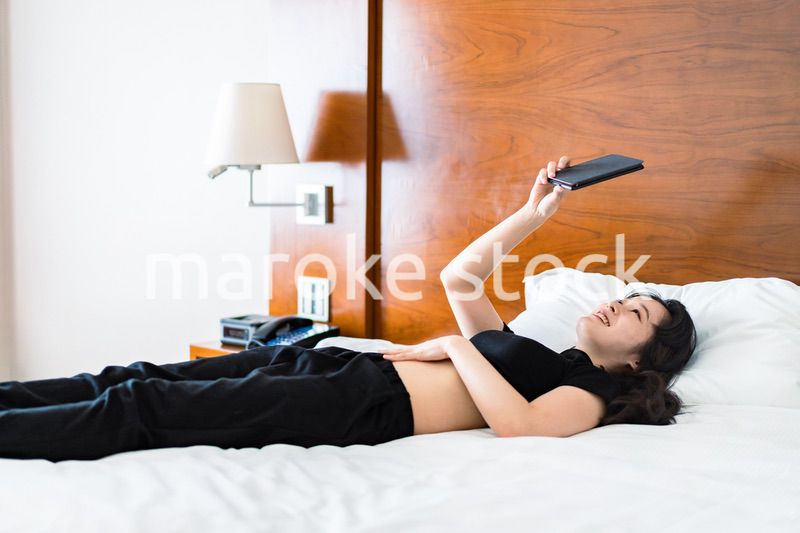 ベッドで電子書籍を読む若い女性