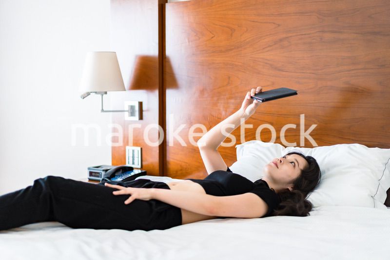 ベッドで電子書籍を読む若い女性