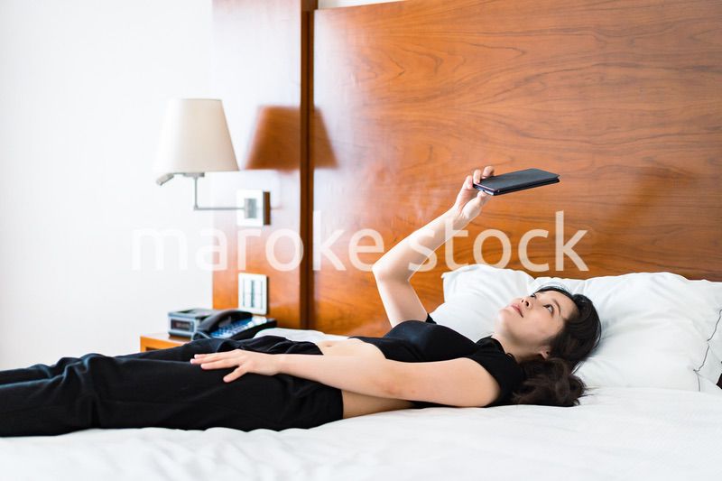 ベッドで電子書籍を読む若い女性