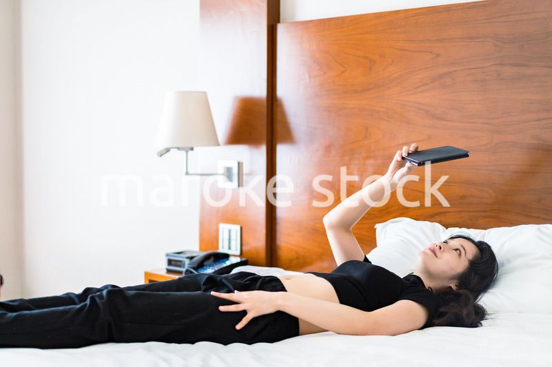 ベッドで電子書籍を読む若い女性