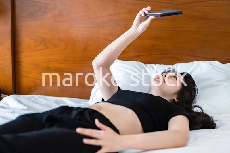 ベッドで電子書籍を読む若い女性