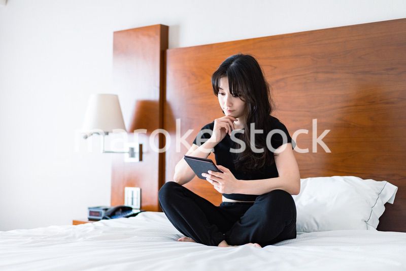 ベッドで電子書籍を読む若い女性