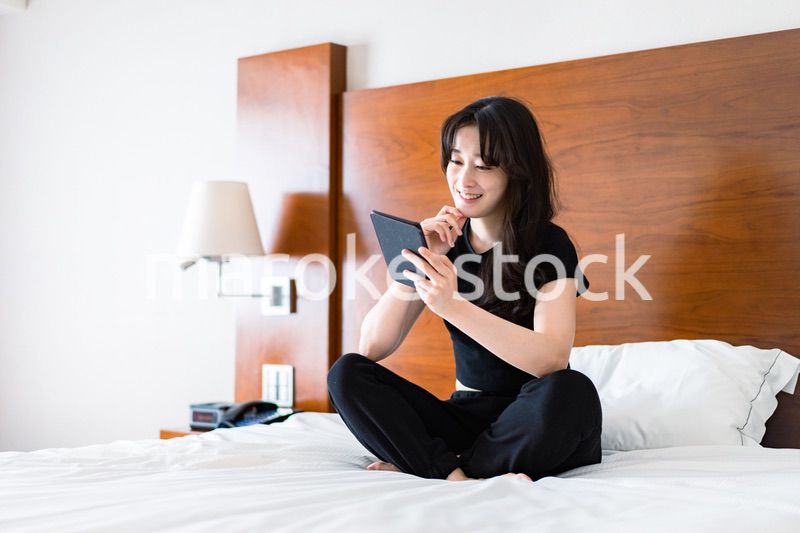 ベッドで電子書籍を読む若い女性