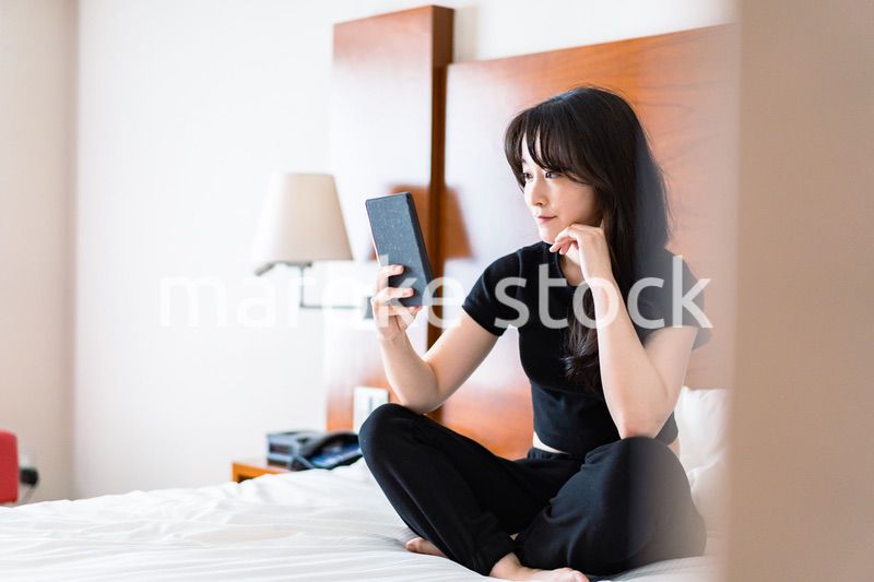 ベッドで電子書籍を読む若い女性