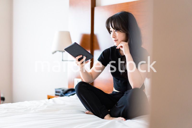 ベッドで電子書籍を読む若い女性