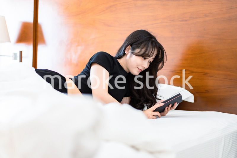ベッドで電子書籍を読む若い女性
