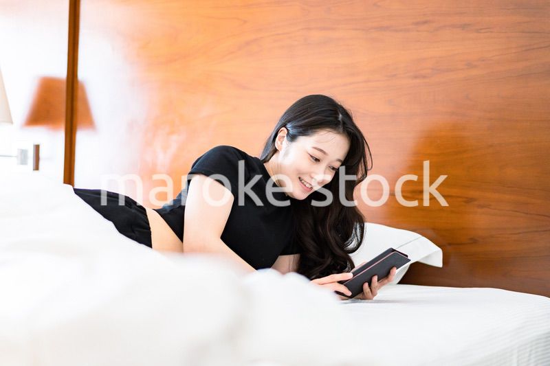 ベッドで電子書籍を読む若い女性