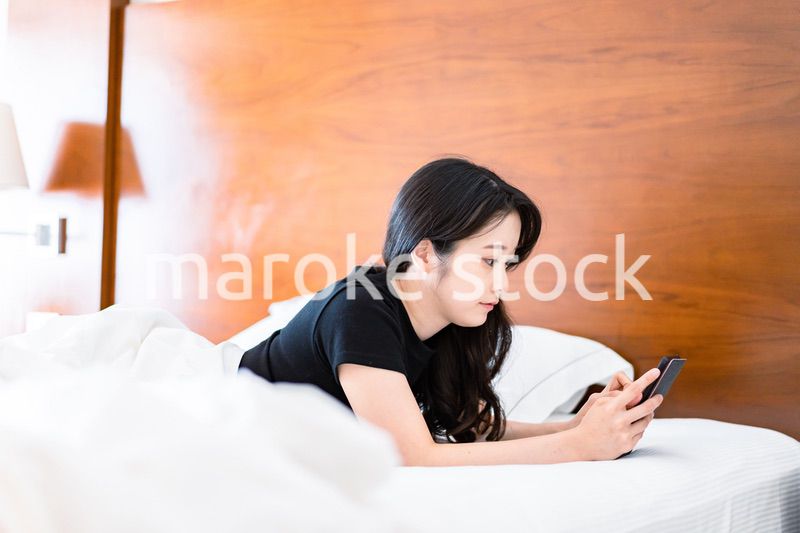 ベッドで電子書籍を読む若い女性