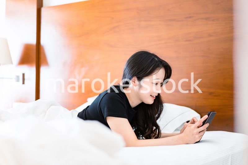 ベッドで電子書籍を読む若い女性